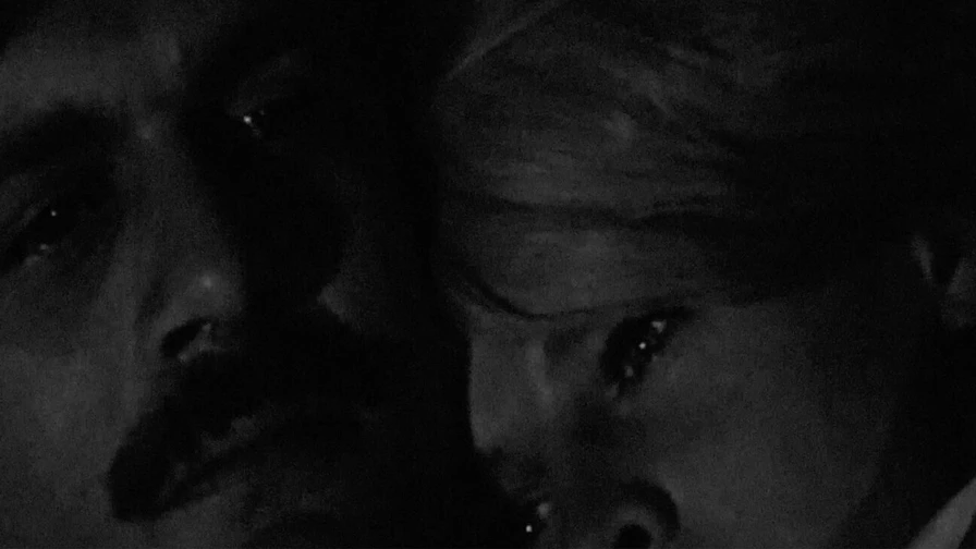 dimly lit black and white image, two people are closely embracing, conveying intimacy and emotion