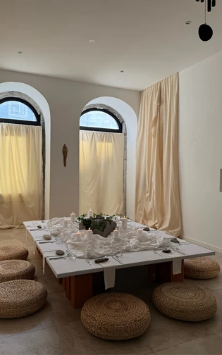 A minimalist dining room with a low table surrounded by woven cushions.